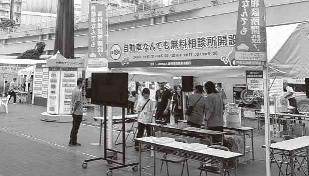 名古屋・栄のオアシス21銀河の広場に開設された第18回「自動車なんでも無料相談所」の会場風景とNASVAのシンボルキャラクター・ナスバちゃん